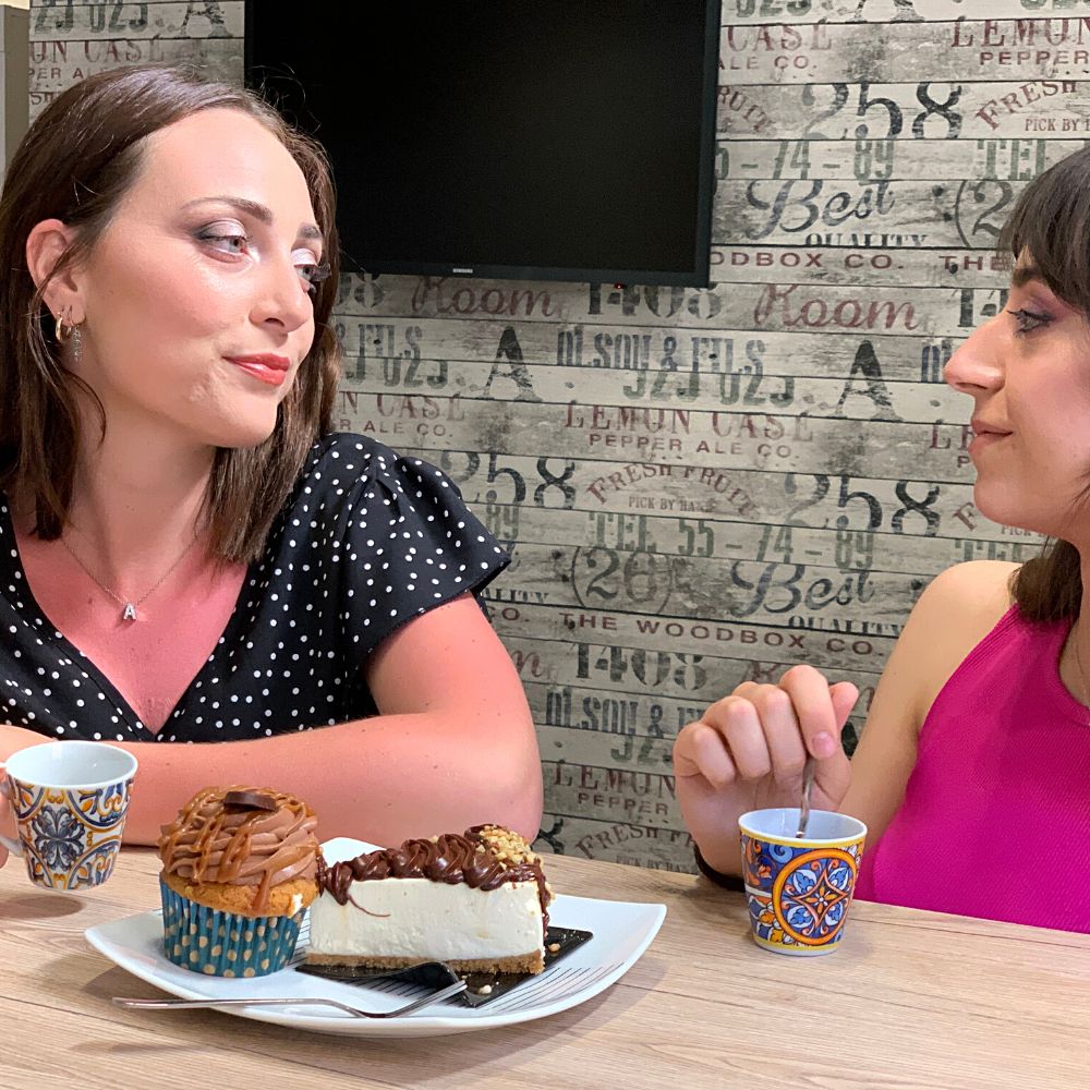 2 tazzine da caffè e piattini e due amiche che fanno colazione