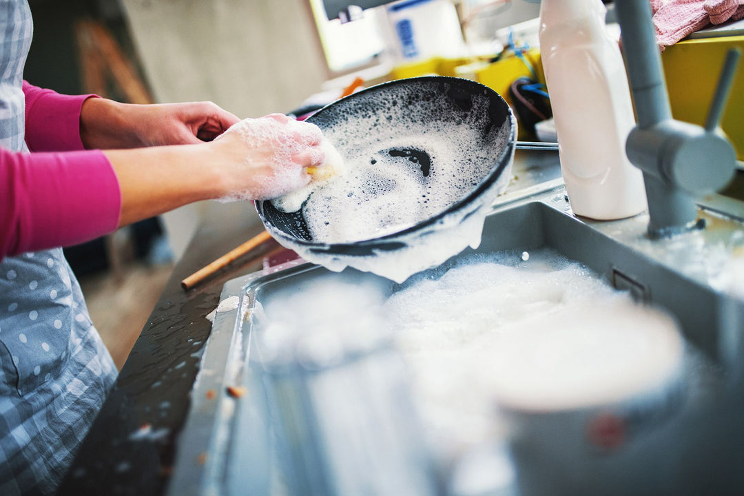 donna che lava padella con sapone in cucina 