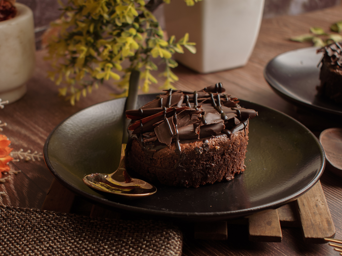 Tortino al cioccolato  su piatto nero e cucchiaio gold