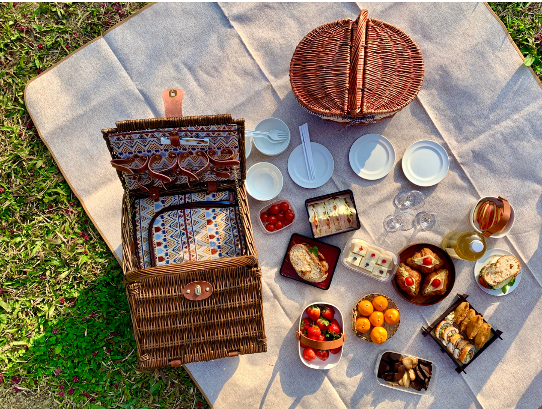 pic nic con cesto e buon cibo apparecchiato su prato 
