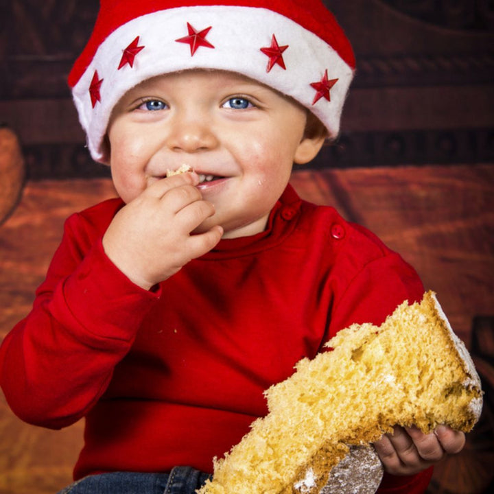 Bambino che mangia pandoro vestito da natale